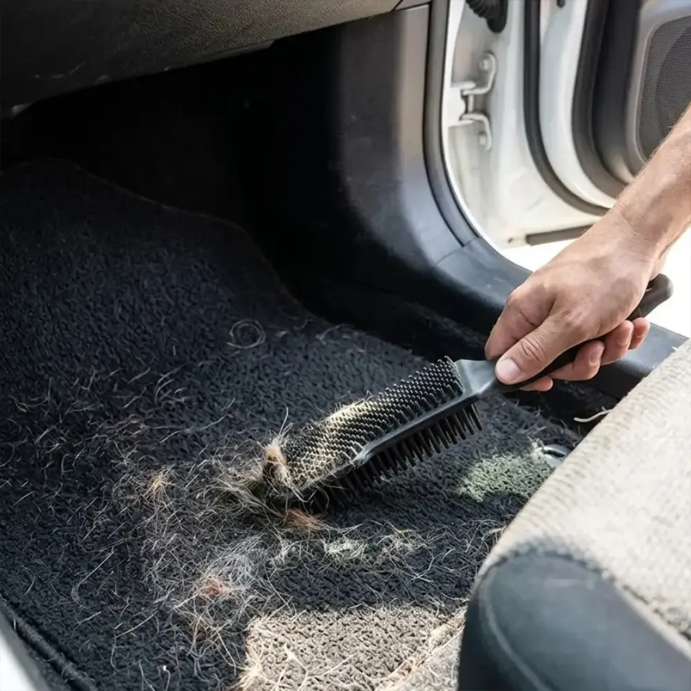 Hand verwijdert dierenharen uit een automat met een rubberen borstel