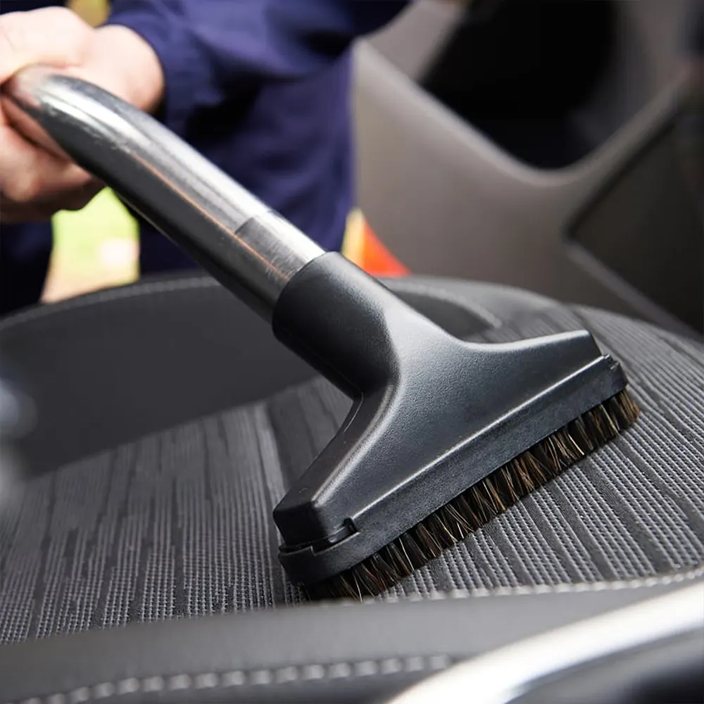 Medewerker zuigt een autostoel met een borstelmond